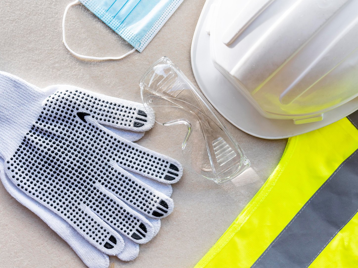 Safety gloves, goggles, mask, helmet and hi-vis vest laid out together